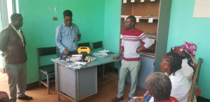 Men and women looking at a solar power lamp that is on a desk.